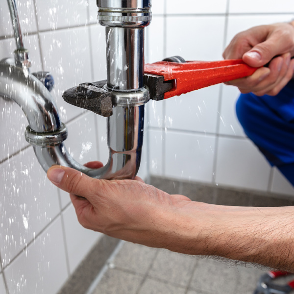 professional with wrench working on drain cleaning project